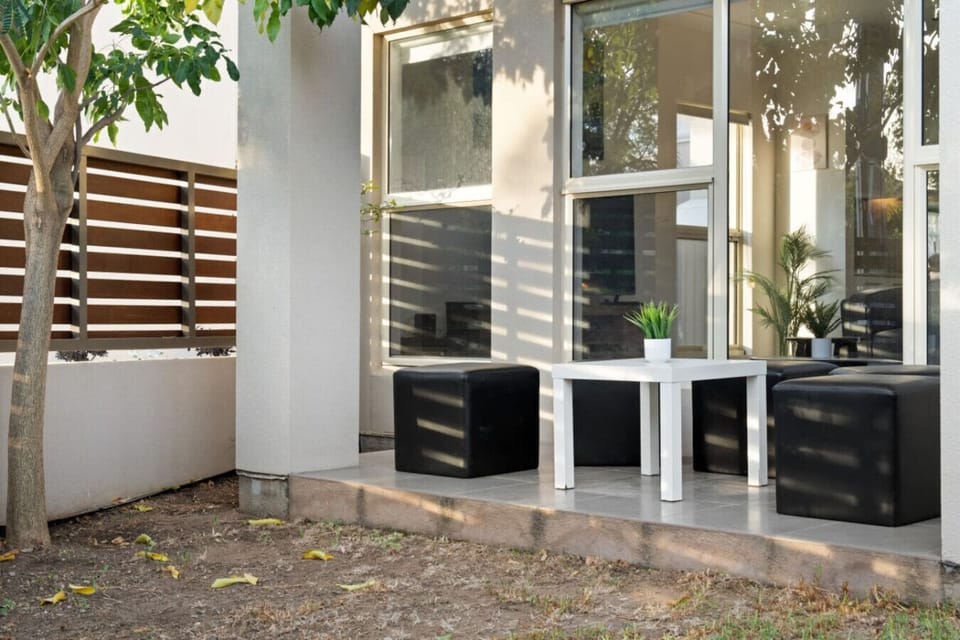 Relax with a morning coffee under the shaded front patio, surrounded by lush greenery.
