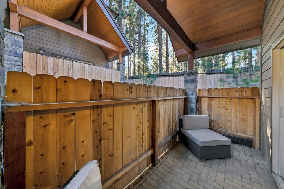 Unwind on your private patio with modern outdoor seating surrounded by tall pines and natural wood privacy.