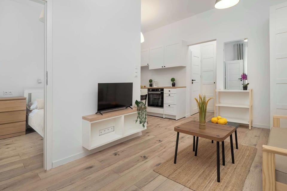 A dining table with two chairs and a tablecloth set near the refrigerator. A framed picture decorates the wall.