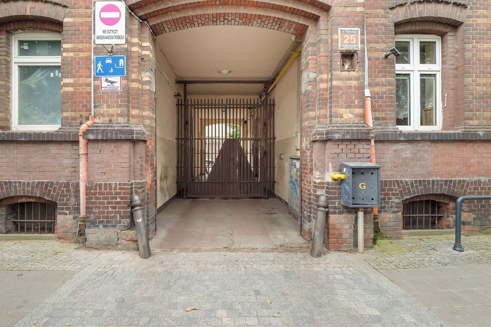 A red brick archway leading into the building’s courtyard. The structure has a classic architectural style.