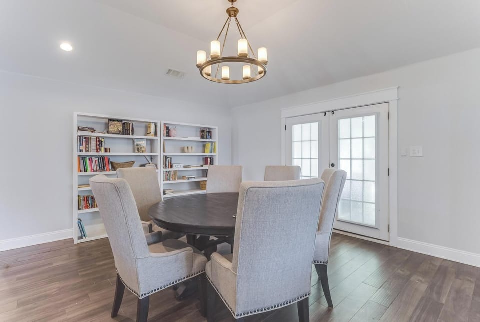 Bright dining area with elegant chandelier and built-in shelving for versatile work or mealtime use.