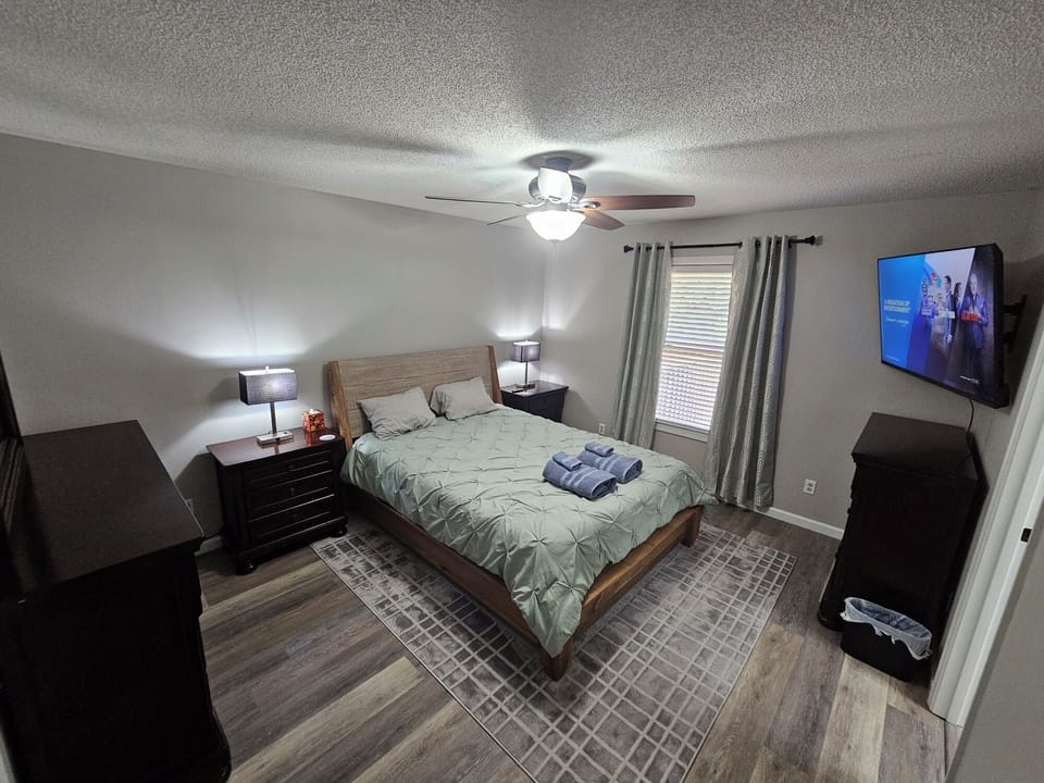 Master Bedroom, queen bed, attached bathroom, TV, blackout curtains.