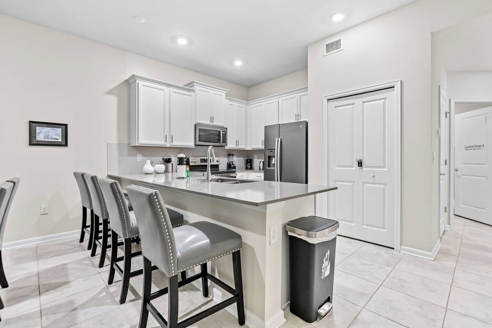 Enjoy a stylish kitchen with chic white cabinetry and a spacious granite island, ideal for casual meals. Modern appliances and shining tile floors provide a bright, functional space for your culinary adventures.
