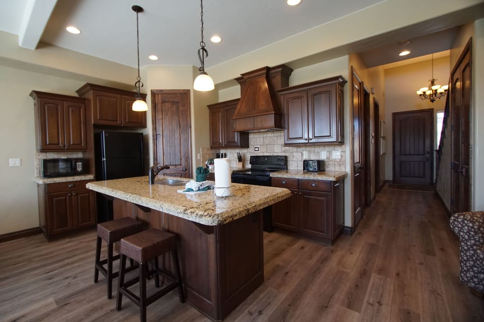 Modern kitchen with full appliances, island seating, and warm wood cabinetry.
