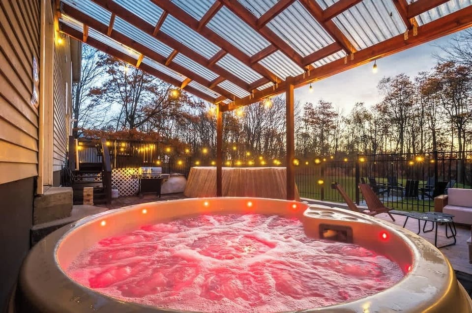 Unwind in the glowing hot tub beneath the wooden pergola at dusk