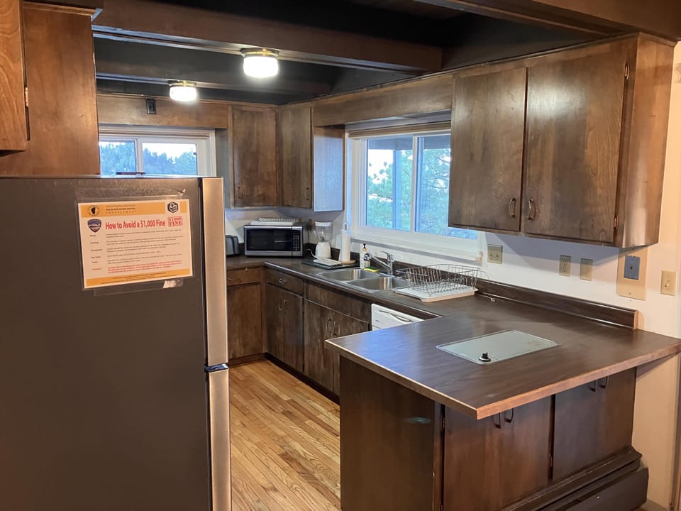 Rustic kitchen with wood cabinetry and a view of the outdoors.