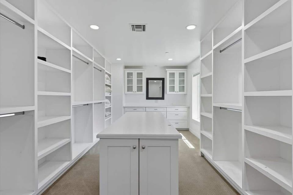 Primary bathroom featuring a dual vanity, stand-in shower, bathtub, and large walk-in closet.