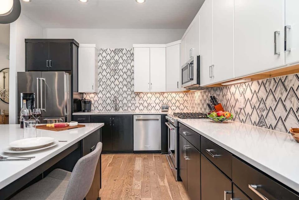 The fully equipped modern kitchen is stocked with all culinary essentials, stainless-steel appliances, and breakfast bar seating.