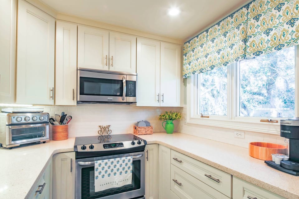 The renovated kitchen features stainless steel appliances, a double window and white cabinetry.