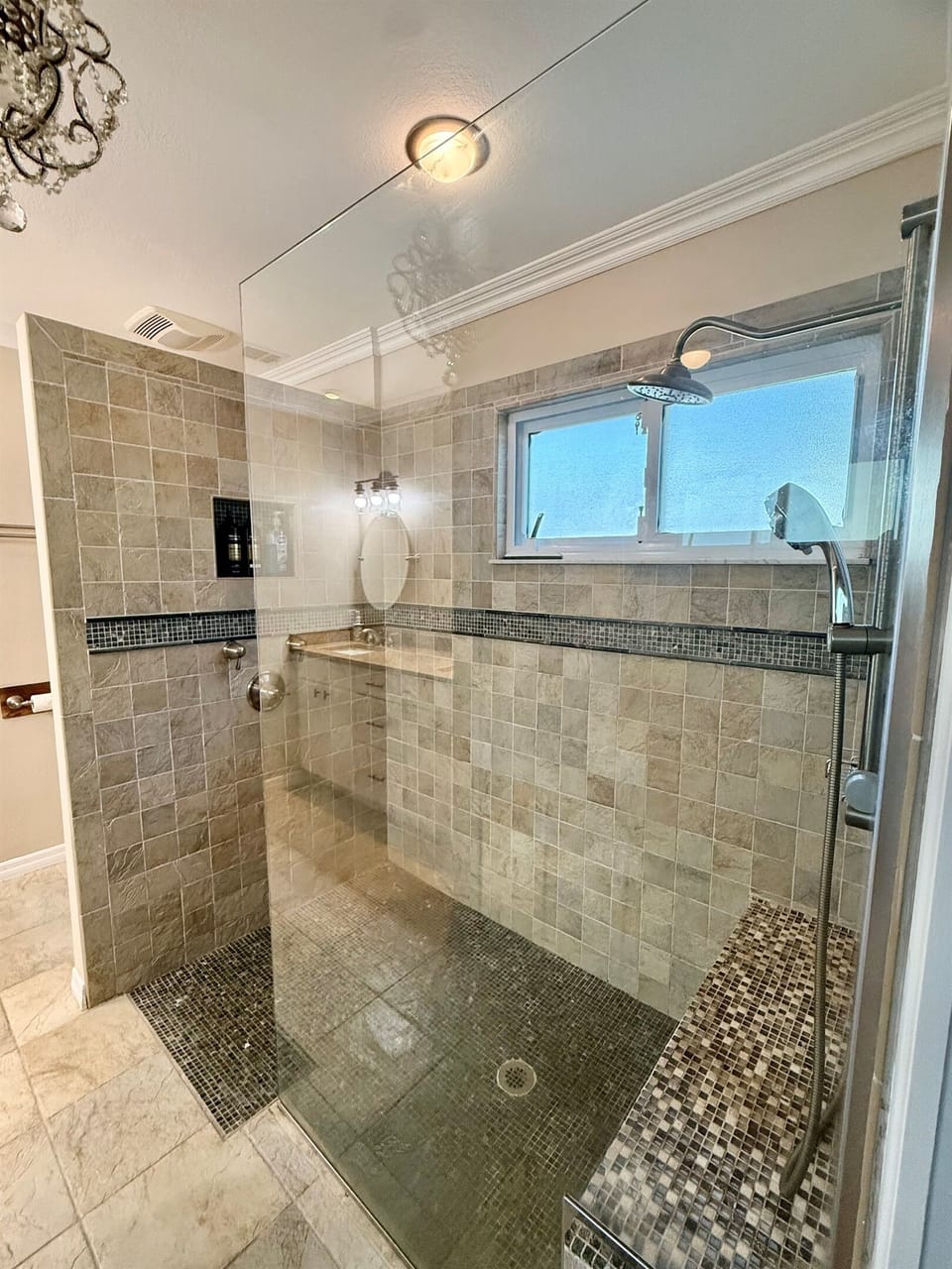Glass-enclosed primary shower with updated tile and modern fixtures