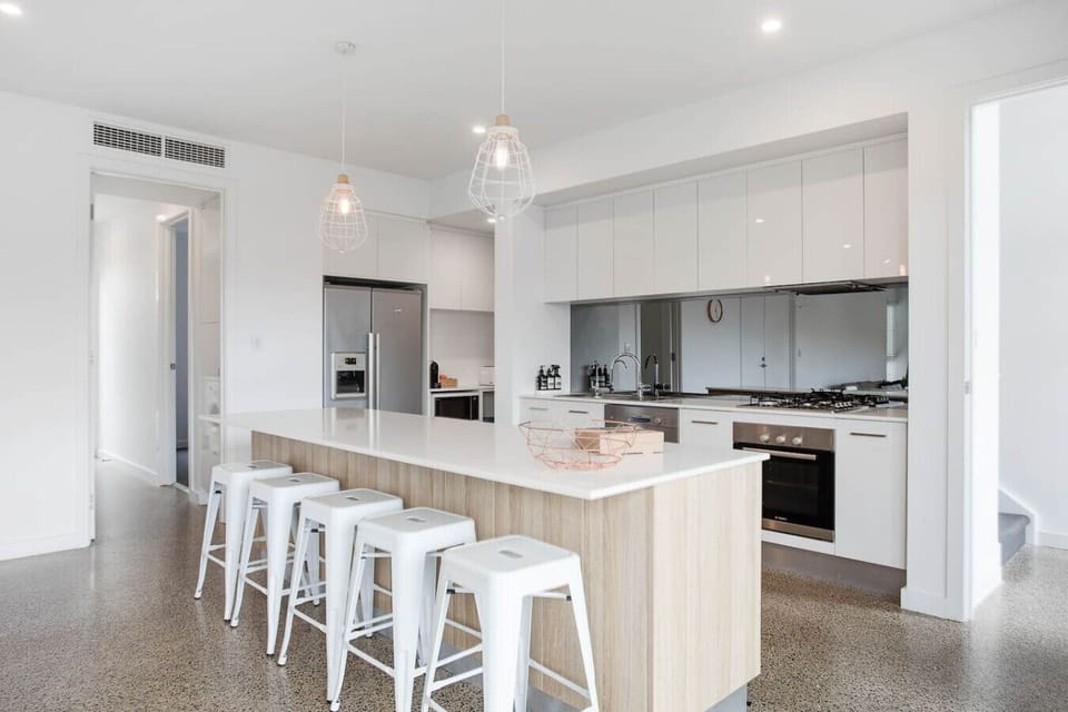 Start the day with coffee and conversation in the sleek coastal kitchen, designed for both style and ease.