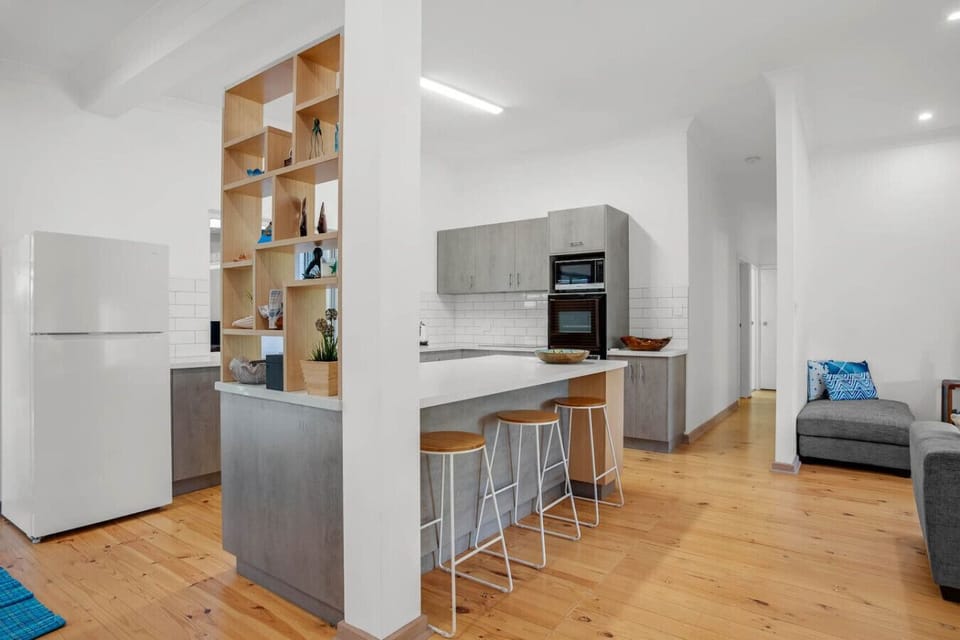 The modern kitchen features sleek cabinetry, full-size appliances, a Nespresso machine, and a breakfast bar with stools.