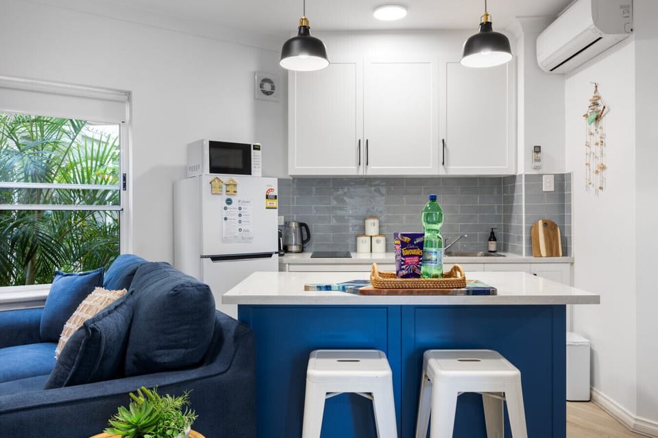 The kitchen pairs sleek cabinetry and a bold blue island with quality appliances and cooking essentials, making meal preparation simple and enjoyable.