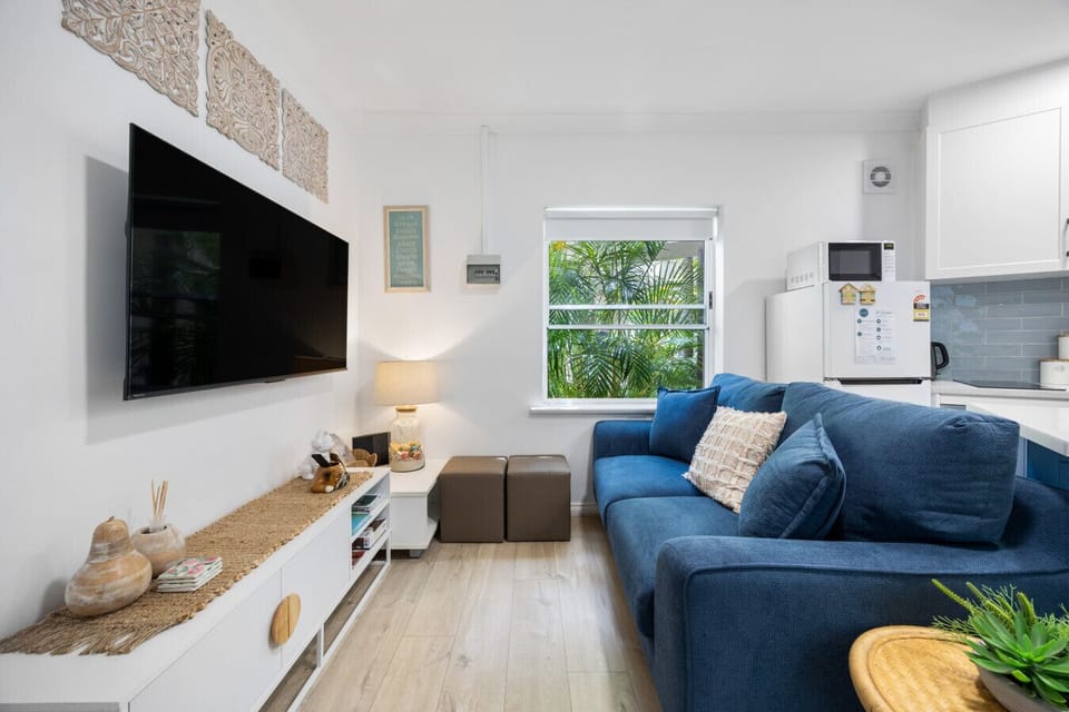 Unwind in the inviting lounge area, where soft seating, natural light, and a wall-mounted TV create the perfect spot to relax after a day by the sea.