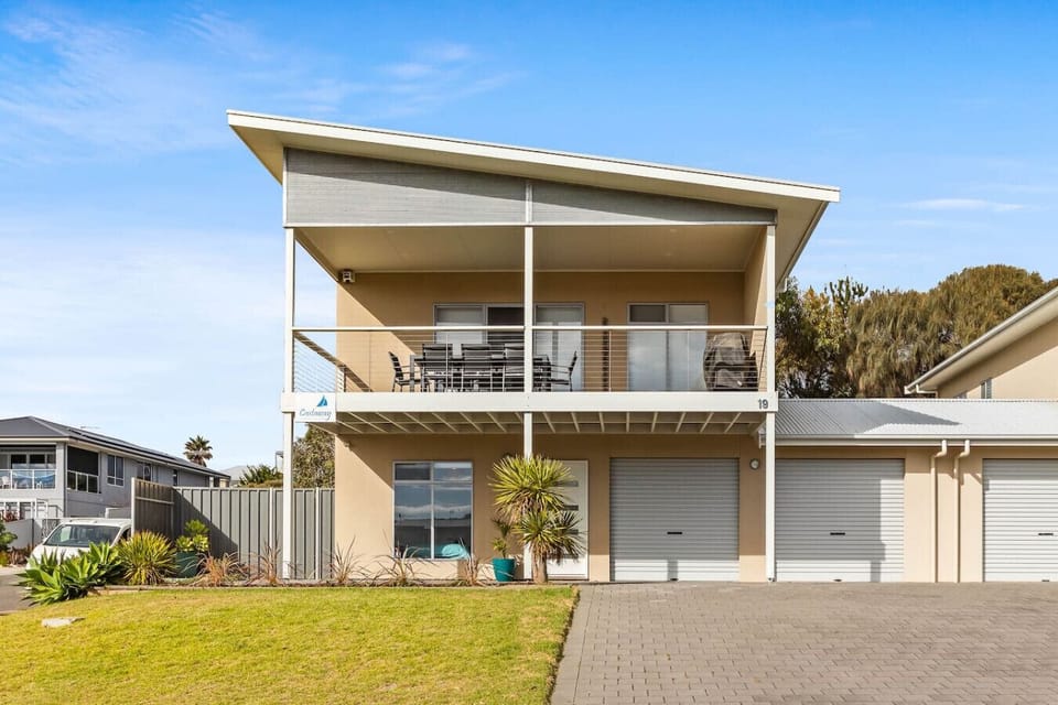 Arrive at a modern coastal façade framed by landscaped gardens and private parking, setting the tone for easygoing comfort.