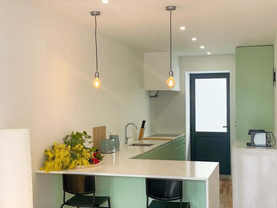 A cozinha está totalmente equipada e integra-se harmoniosamente com a zona de refeições. O balcão com bancos altos permite refeições rápidas ou pequenos-almoços ao sol. Equipada com placa, forno, micro-ondas, máquina de café, jarro elétrico, torradeira e todos os utensílios essenciais para estadias curtas ou prolongadas.
