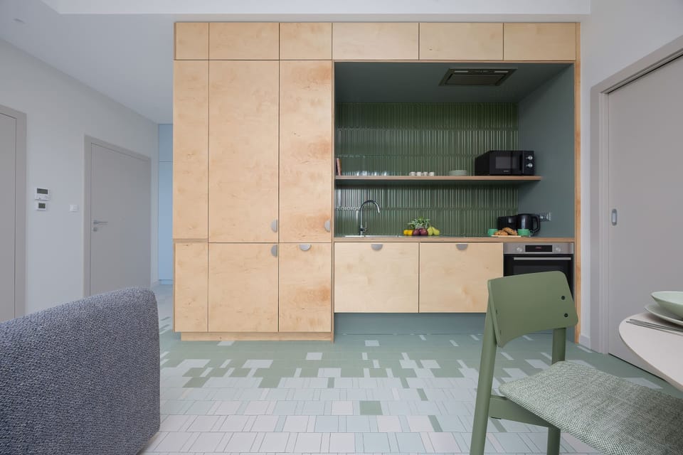 The modern kitchenette with green accents and a practical table ensures comfort for cooking meals and enjoying time together.