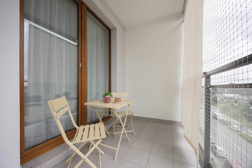 A balcony equipped with a small table and two chairs, secured with safety mesh. Perfect for outdoor relaxation.