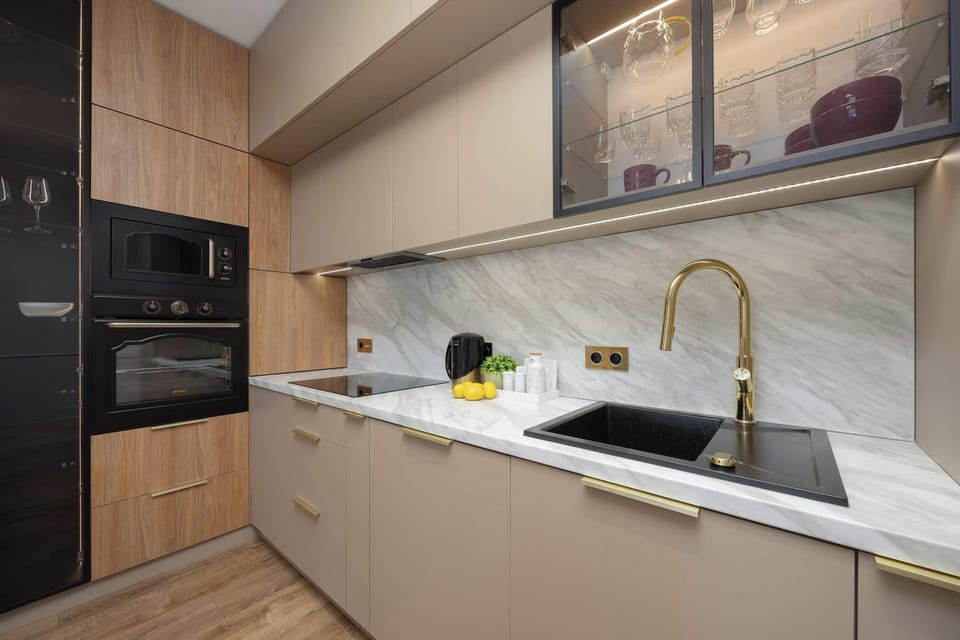 A sleek kitchen with wooden cabinets, marble backsplash, and black built-in appliances. The countertop offers both style and functionality.