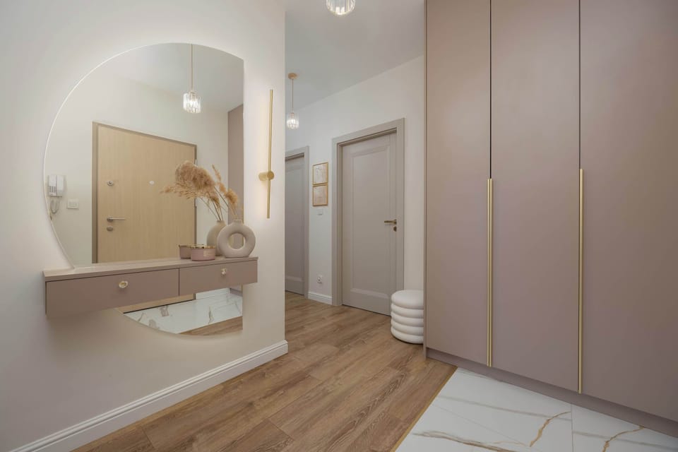 A hallway with fitted wardrobes and wooden flooring. The wide entryway feels functional and bright.