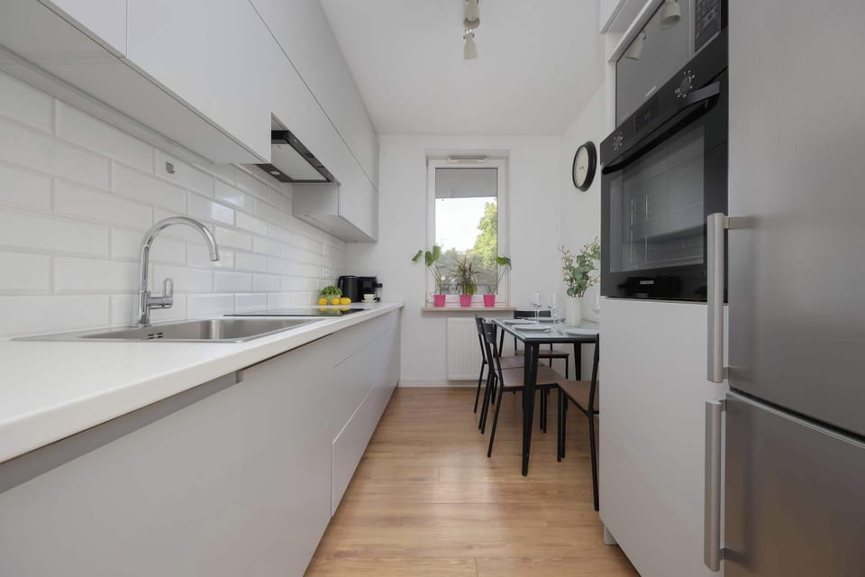 The modern kitchen with bright cabinets and a wooden dining table invites you to cook together and enjoy meals comfortably.