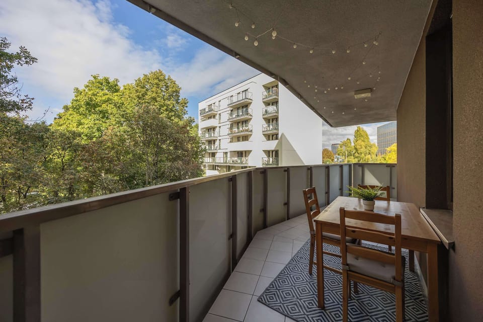 From the balcony, you can admire the surrounding trees and modern buildings, offering a sense of space and closeness to nature.