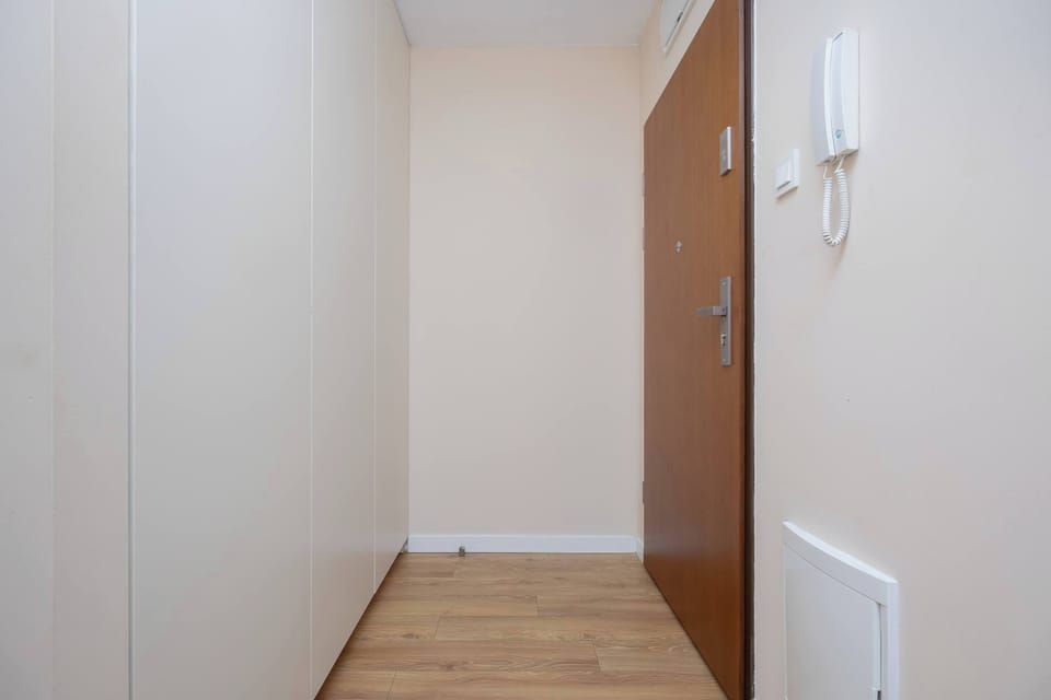 The hallway with light walls and wooden flooring welcomes guests with simplicity and functionality.