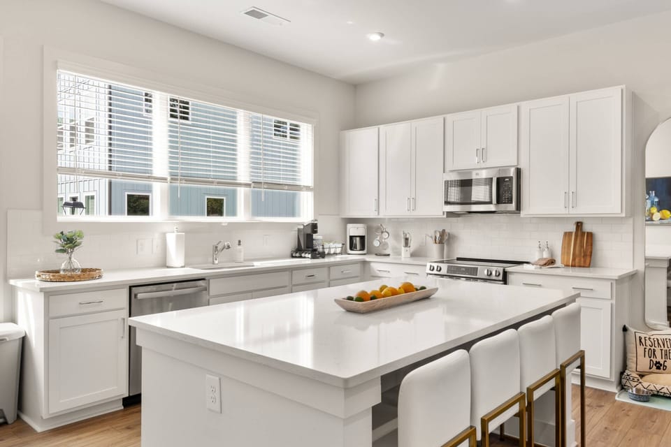 Sleek Open Kitchen | Family-Friendly Atlanta Short-Term Rental Crisp white cabinetry & high-end finishes make this kitchen a guest favorite.