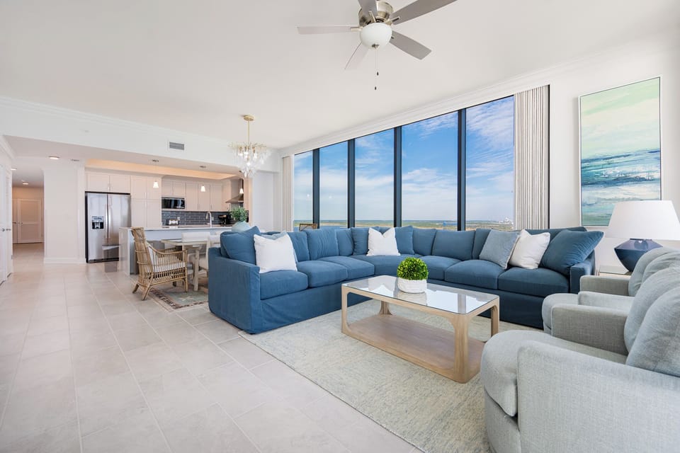 Spacious living area with a large sectional, enjoying views through expansive windows that invite natural light