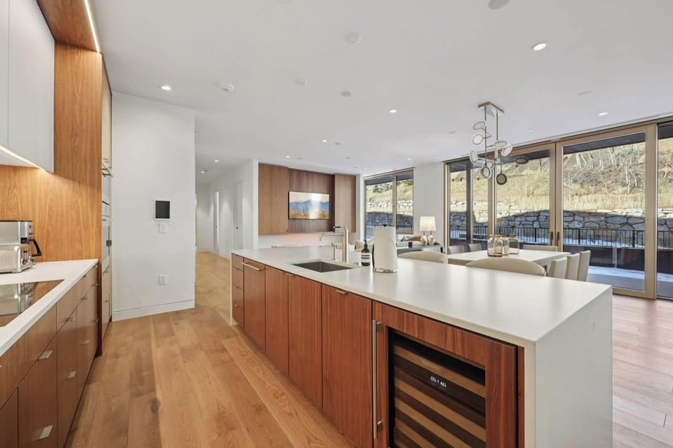 Your sleek kitchen boasts warm wood cabinetry and pristine countertops, with floor-to-ceiling windows flooding the space with natural light.