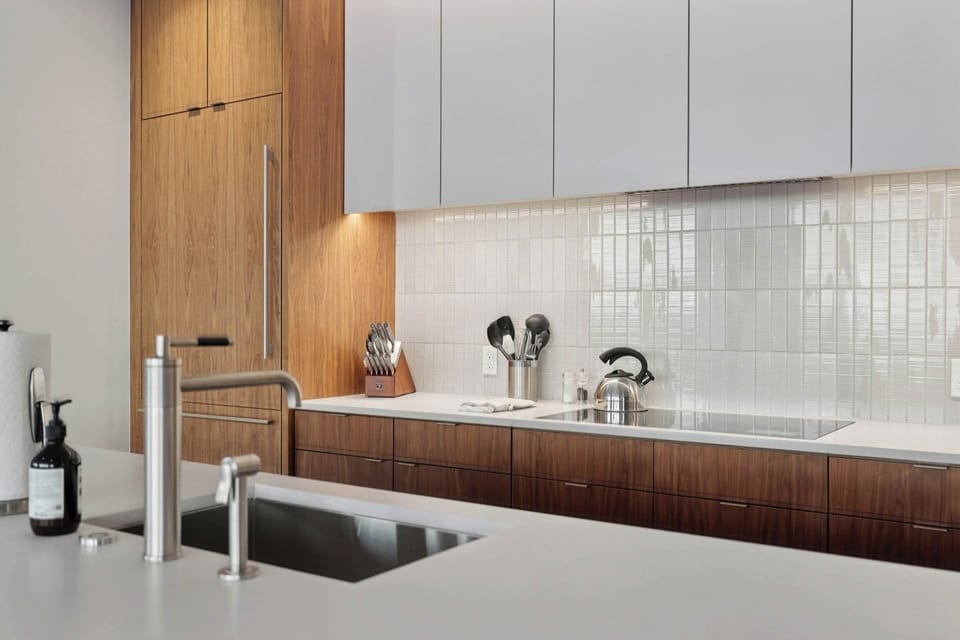 Your sleek modern kitchen features warm wood cabinetry and pristine countertops, perfect for preparing meals during your stay.
