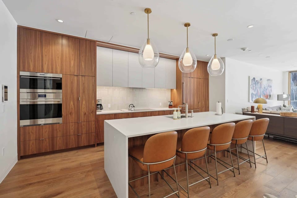 Your culinary haven features rich walnut cabinetry, sleek pendant lighting, and a spacious island for memorable meals together.