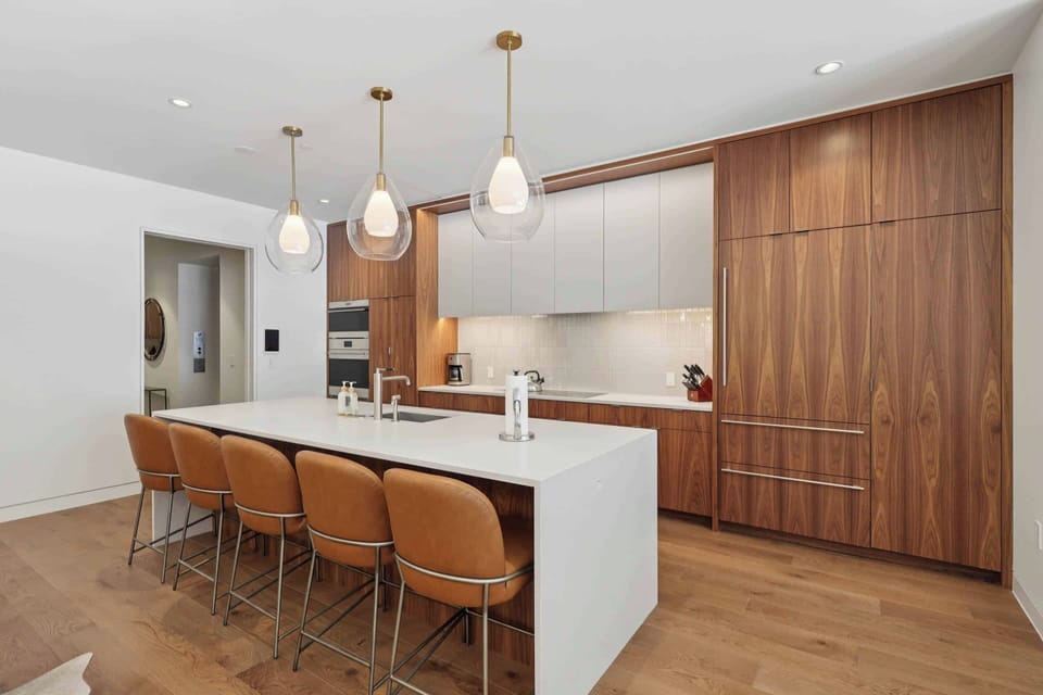 Your sleek modern kitchen features warm walnut cabinetry, pristine quartz countertops, and pendant lighting creating the perfect space for cooking.