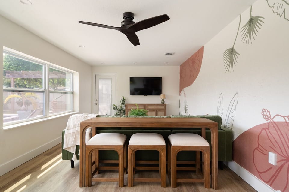 Game room with a couch, ceiling fan, large window, wall art, and Smart TV.