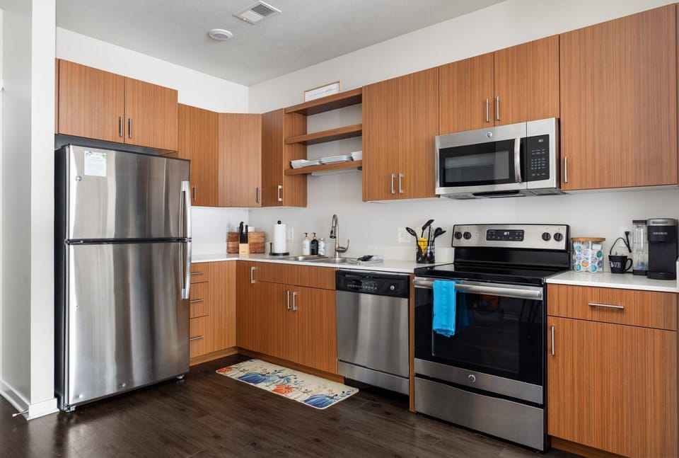 Modern kitchen w/ stainless steel appliances, warm wood cabinets, & plenty of counter space