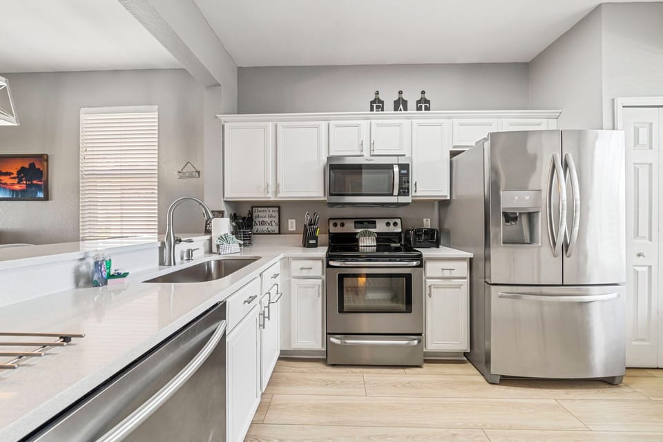 A kitchen sink area with warm cabinetry and modern appliances.