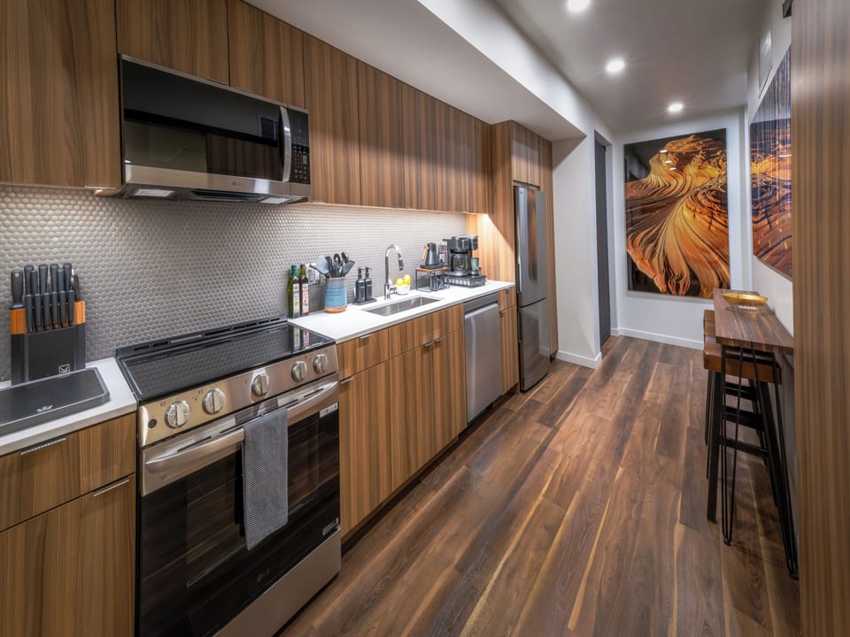 A warm, contemporary kitchen featuring rich walnut cabinetry and white counters.