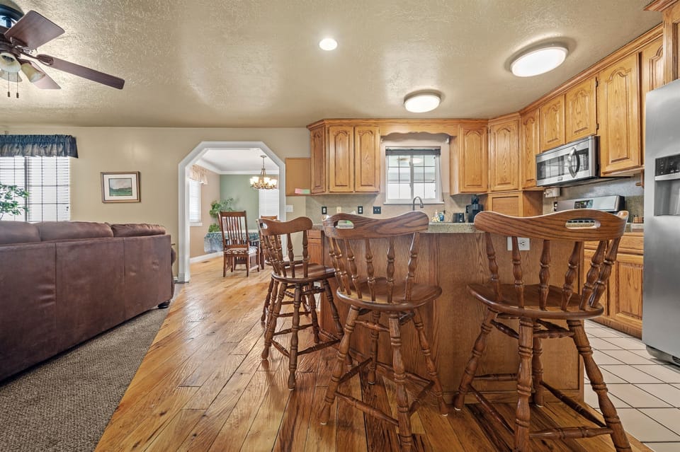 Spacious main level kitchen with natural wood cabinetry and breakfast bar seating — perfect for cooking meals and connecting with family or friends.
