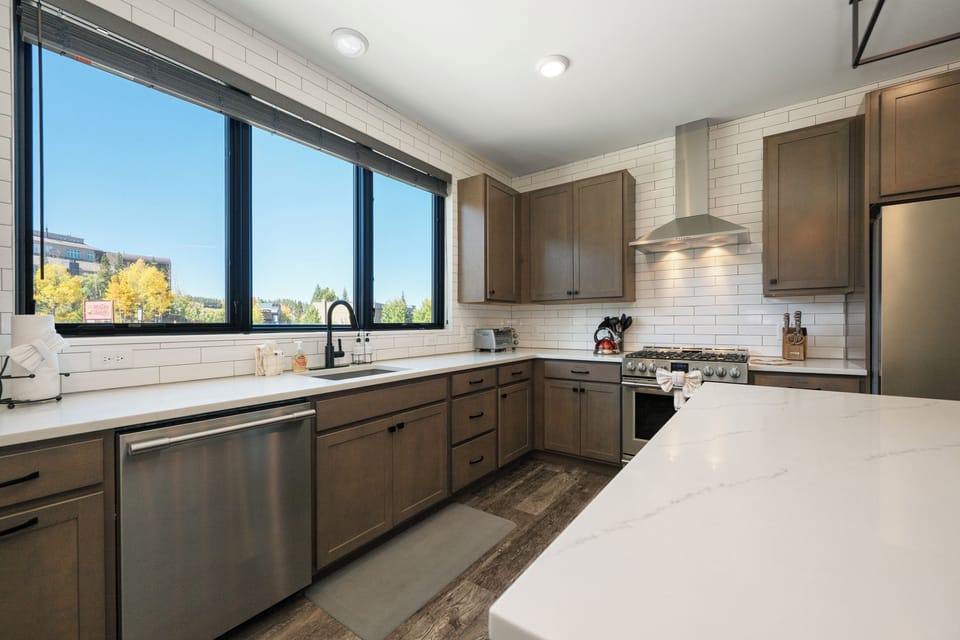 Your modern kitchen features sleek appliances, white quartz counters, and stunning windows that fill the space with natural light.