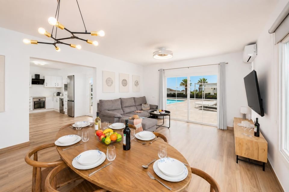 Open-plan living room with sofa, dining area, kitchen, A/C, WiFi internet, and satellite TV