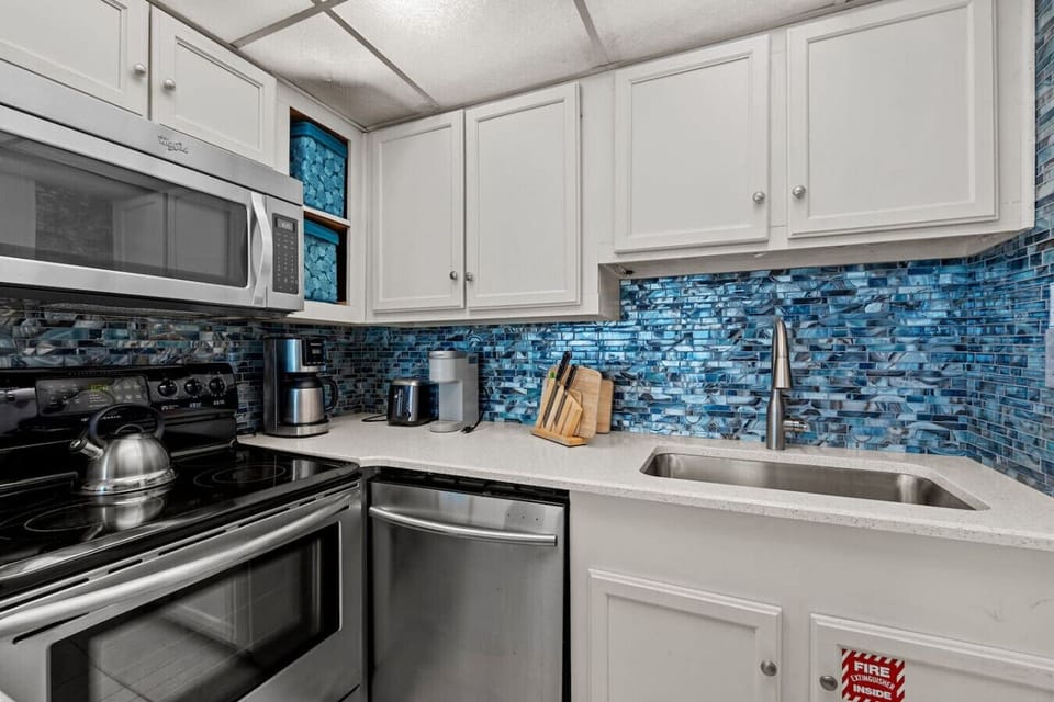 Kitchen Wide View – Modern kitchen with stainless appliances and blue backsplash.