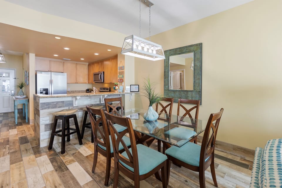 Your open dining area flows seamlessly into the modern kitchen, perfect for gathering around the glass table or chatting at the breakfast bar.