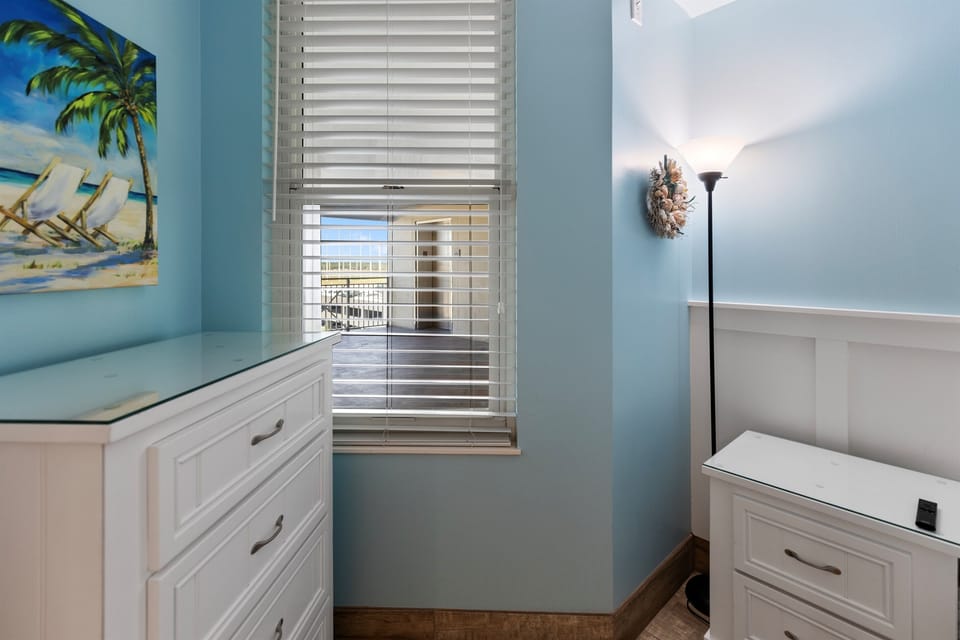 Relax in your coastal-themed bedroom with soothing blue walls, crisp white furniture, and glimpses of the neighborhood through your window.