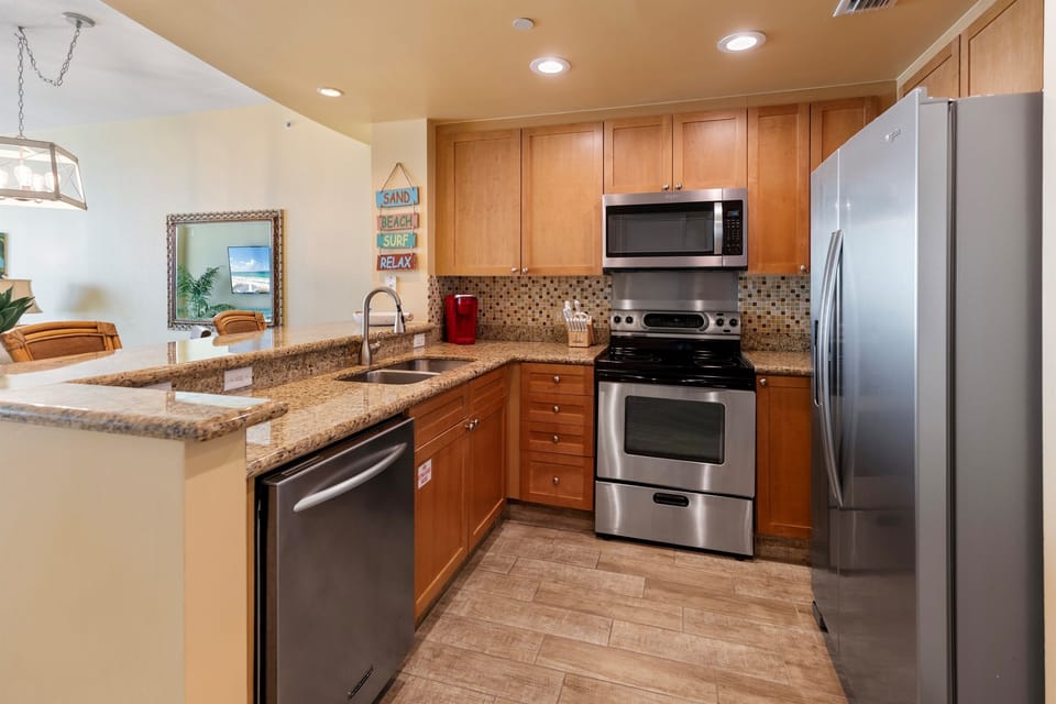 Your fully equipped kitchen features granite counters, stainless appliances, and coastal charm - perfect for preparing meals during your stay.