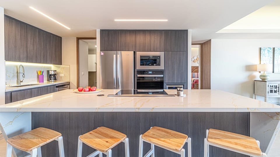 The kitchen island and bar stools, along with modern stainless steel appliances