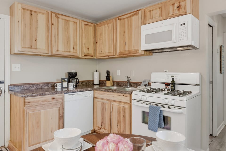 Bright kitchen with natural wood cabinets, coffee essentials, full appliances, and everything needed for easy meals at home.