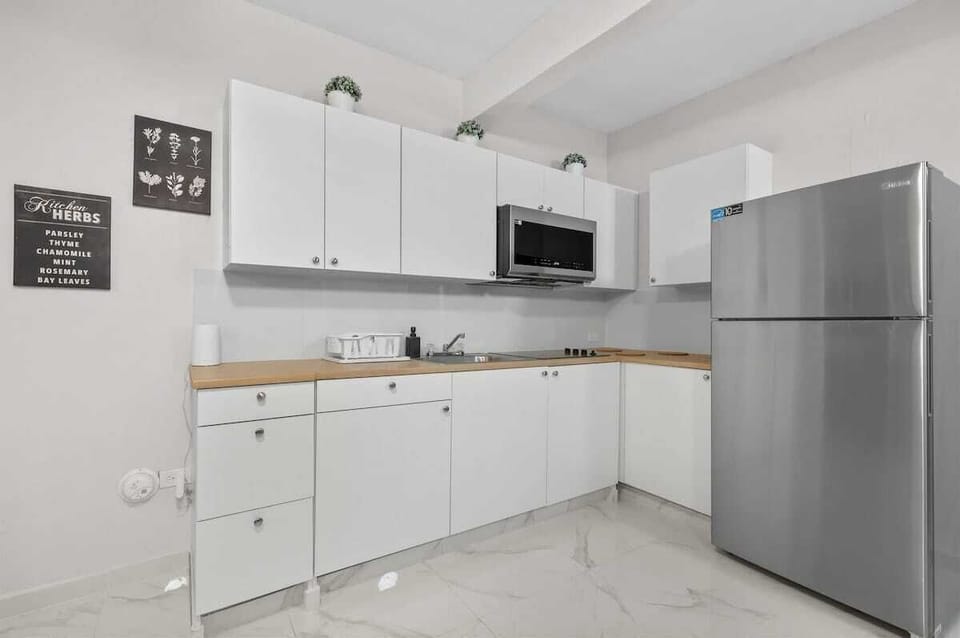 Sleek white cabinets, microwave, and fridge. Ready for snacks.