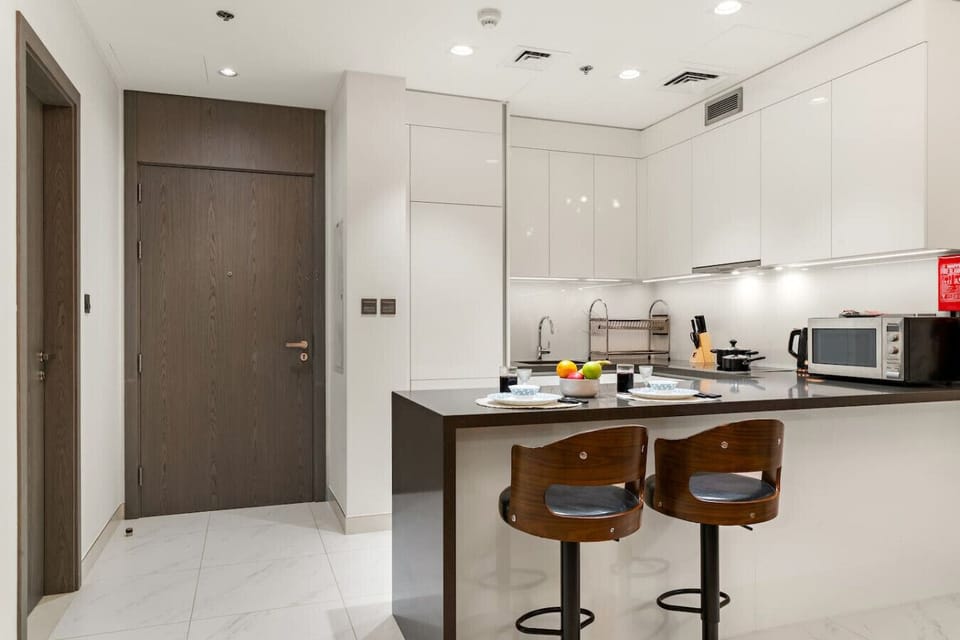 Bright kitchen with island seating, wooden stools, and modern appliances.