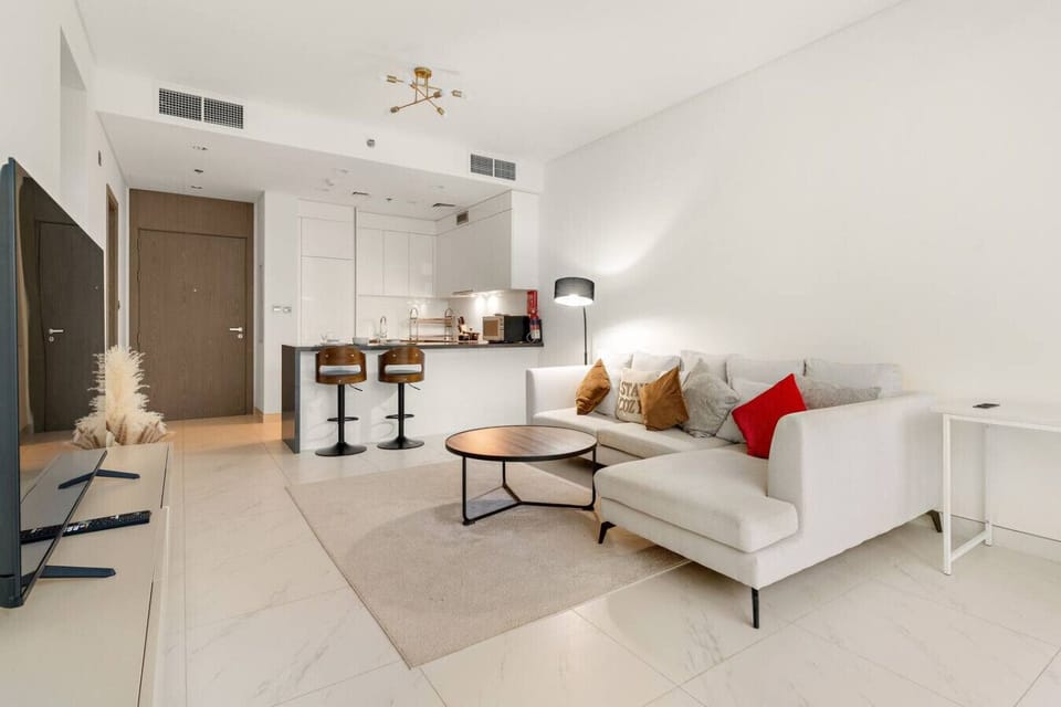 Spacious living room with L-shaped sofa, bar stools, and cozy lighting.
