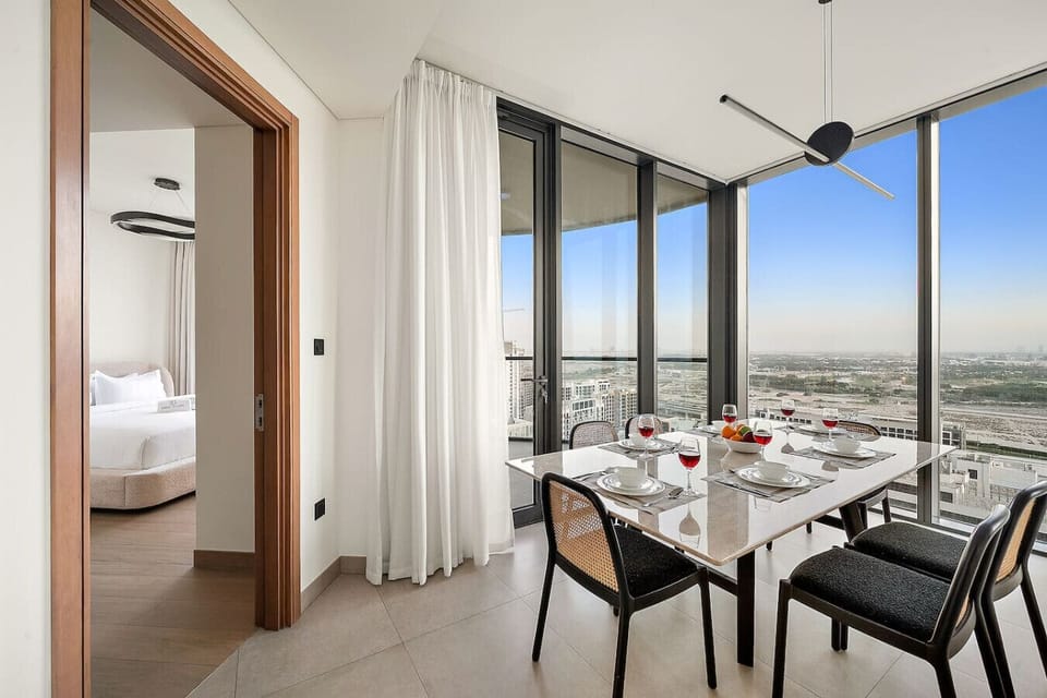 Modern dining area with city view, next to cozy bedroom and floor-to-ceiling windows.